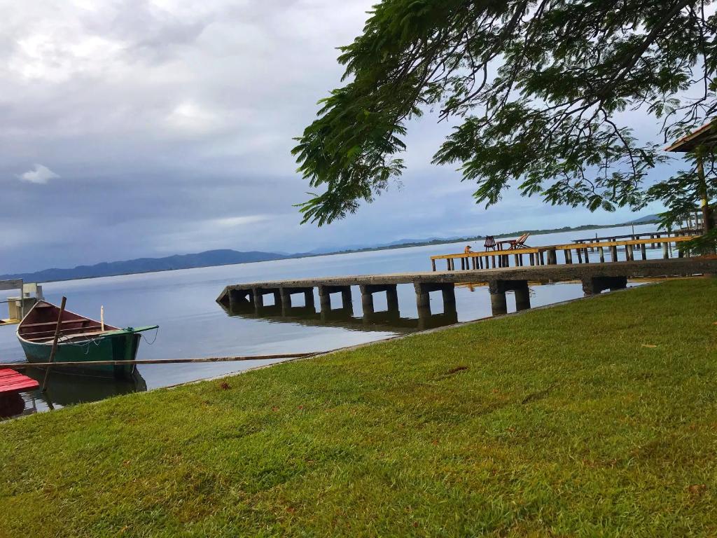 un muelle con un barco junto a un lago en Casa do Tio Rait na frente da Lagoa, en Laguna