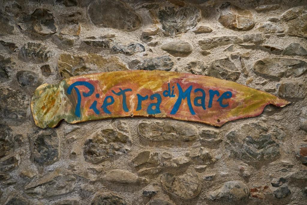 a sign on a stone wall with graffiti on it at Pietra di mare in SantʼAgata di Militello