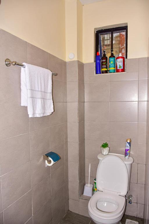 a bathroom with a toilet and a window and towels at Ruby Modern Homes Studio Apt-Imara Daima Behind Imaara Mall-JKIA-Nebula in Nairobi