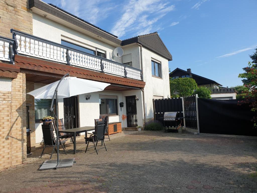 un patio con una mesa y una sombrilla frente a una casa en Ferienwohnung im modernen Ambiente mit eigenem Außenbereich en Waldeck