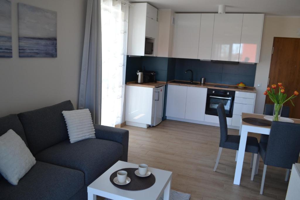 a living room with a couch and a table and a kitchen at Apartament Justynka in Kąty Rybackie