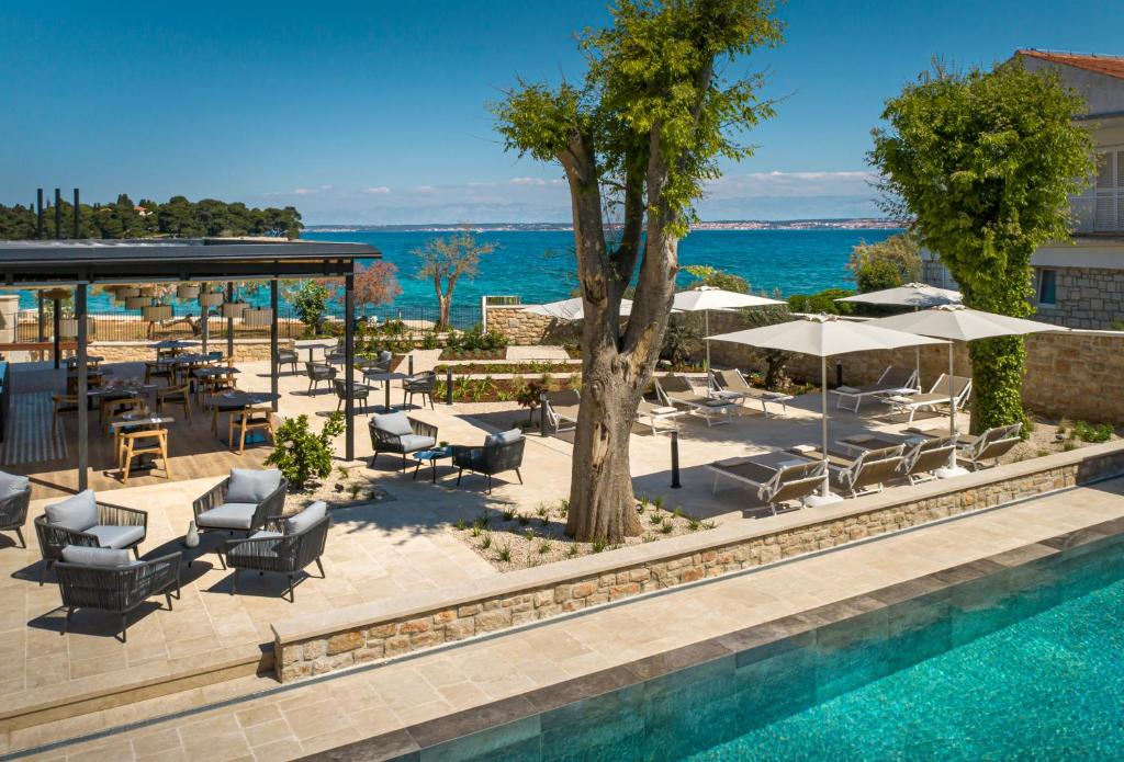 DUNATOVI DVORI Heritage Hotel في بريكو: مسبح مع كراسي جلوس ومظلات بجانب مسبح