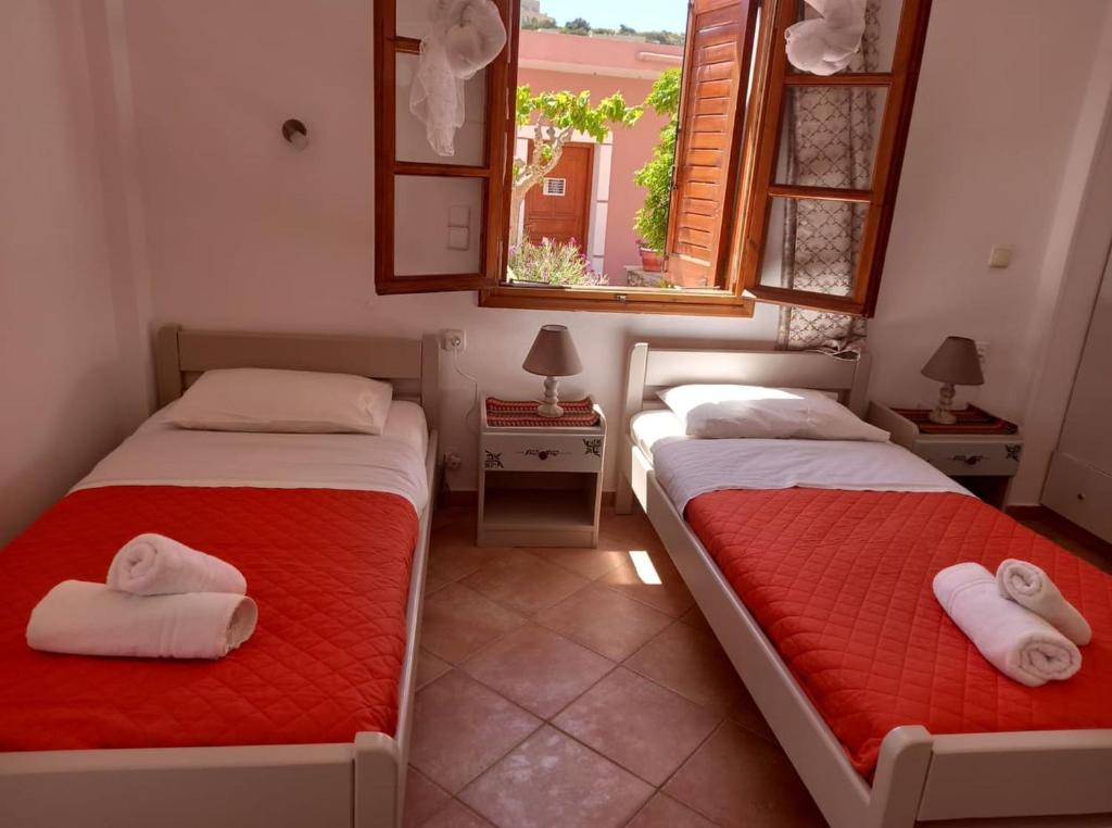 two beds in a room with two windows at Pension Patelo in Pitsidia