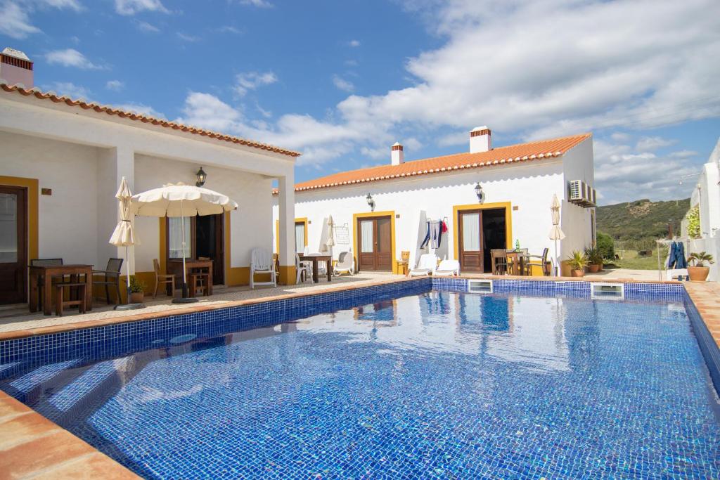 a swimming pool in front of a villa at Carrapateiramar Guest House in Carrapateira