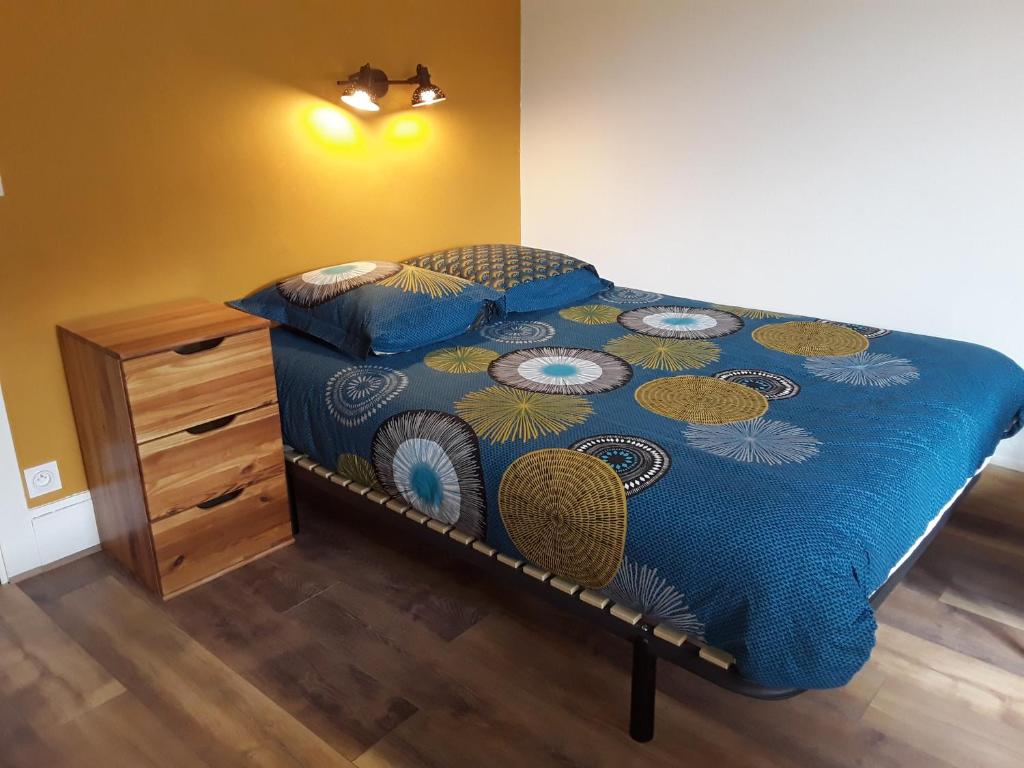 a bed with a blue comforter and a wooden dresser at Deux chambres chez l'habitant in Die