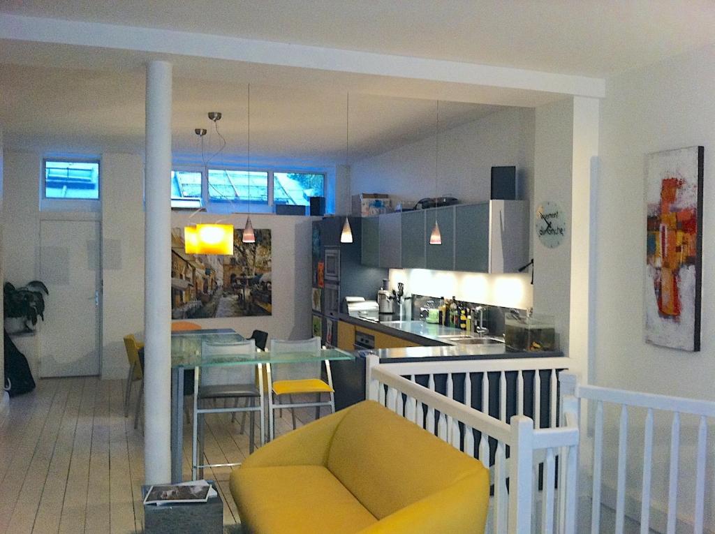 eine Küche und ein Wohnzimmer mit einem Tisch und einem gelben Stuhl in der Unterkunft Modern Design Loft Apartment, Steps to Notre Dame in Paris