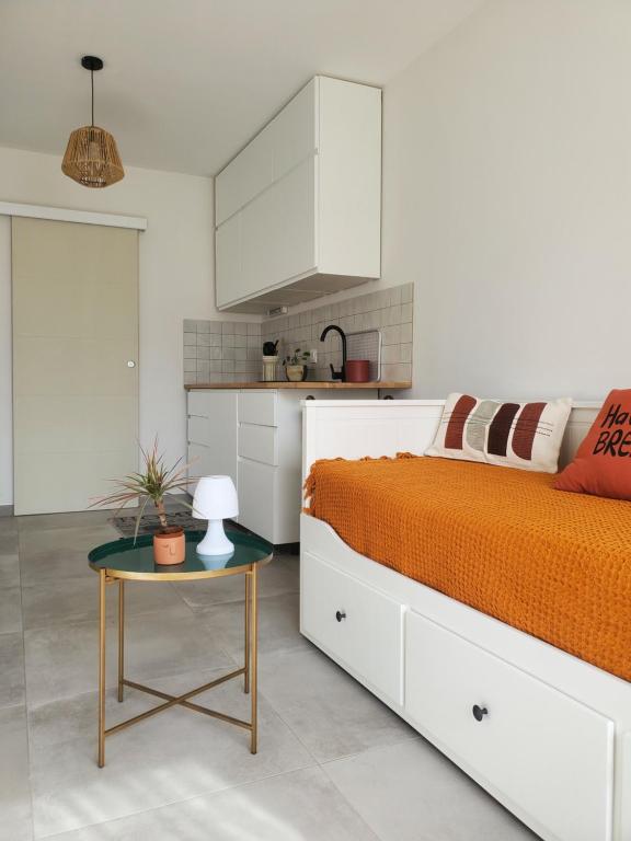 a white bedroom with a bed and a table at Charmant studio moderne avec extérieur "Dormir en provence" in Fontvieille