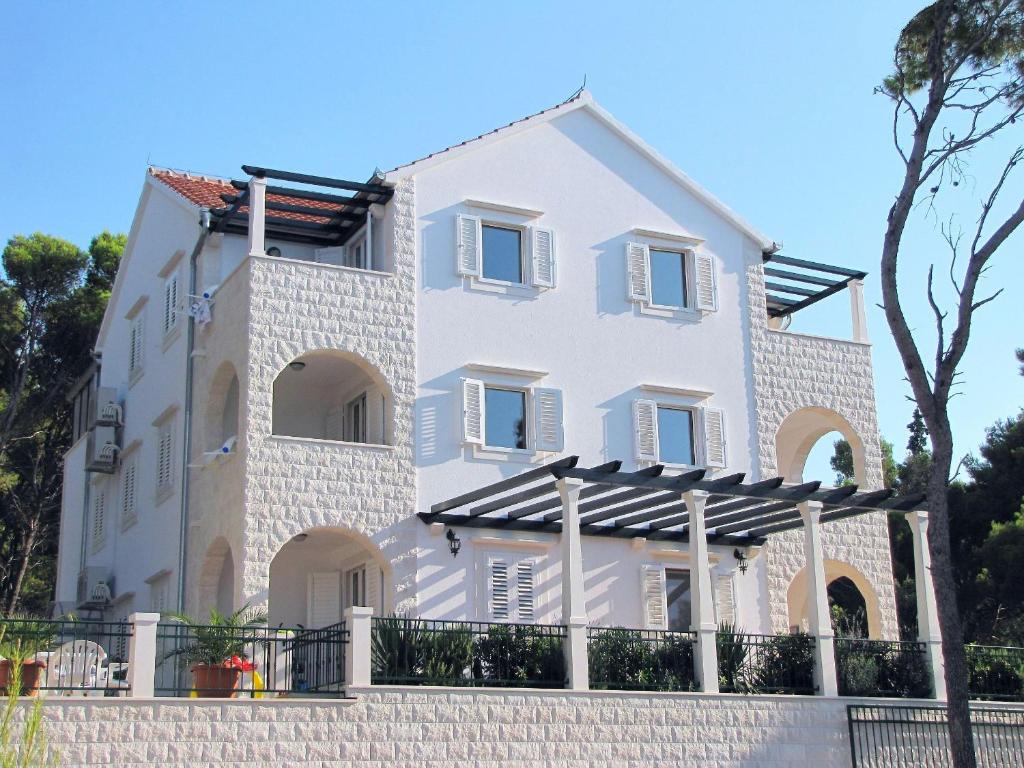 a white house with a fence in front of it at Apartments Villa La Riva - Seafront accommodation in Sutivan