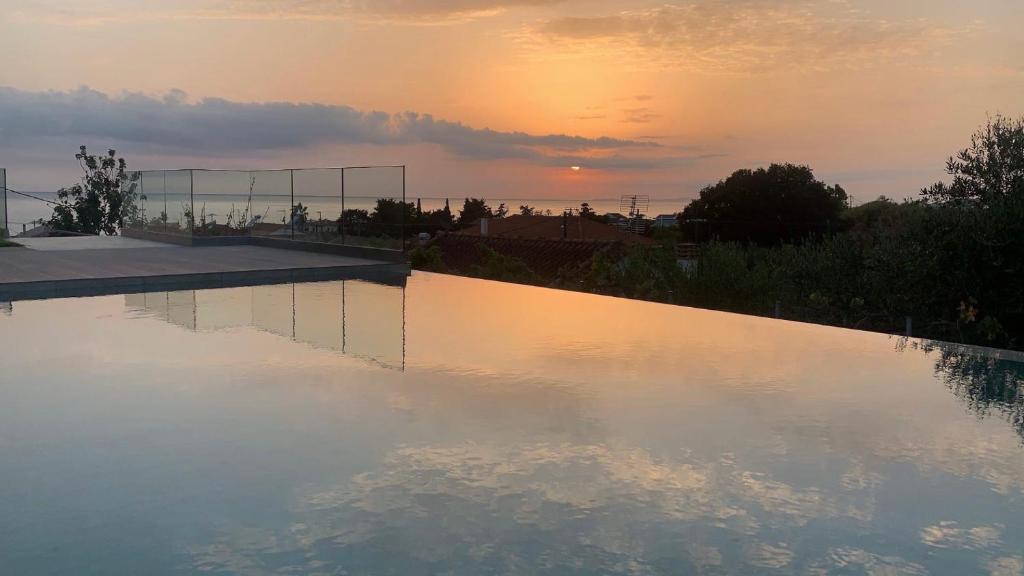 a pool of water with a sunset in the background at Casa Costa Suites in Kanali