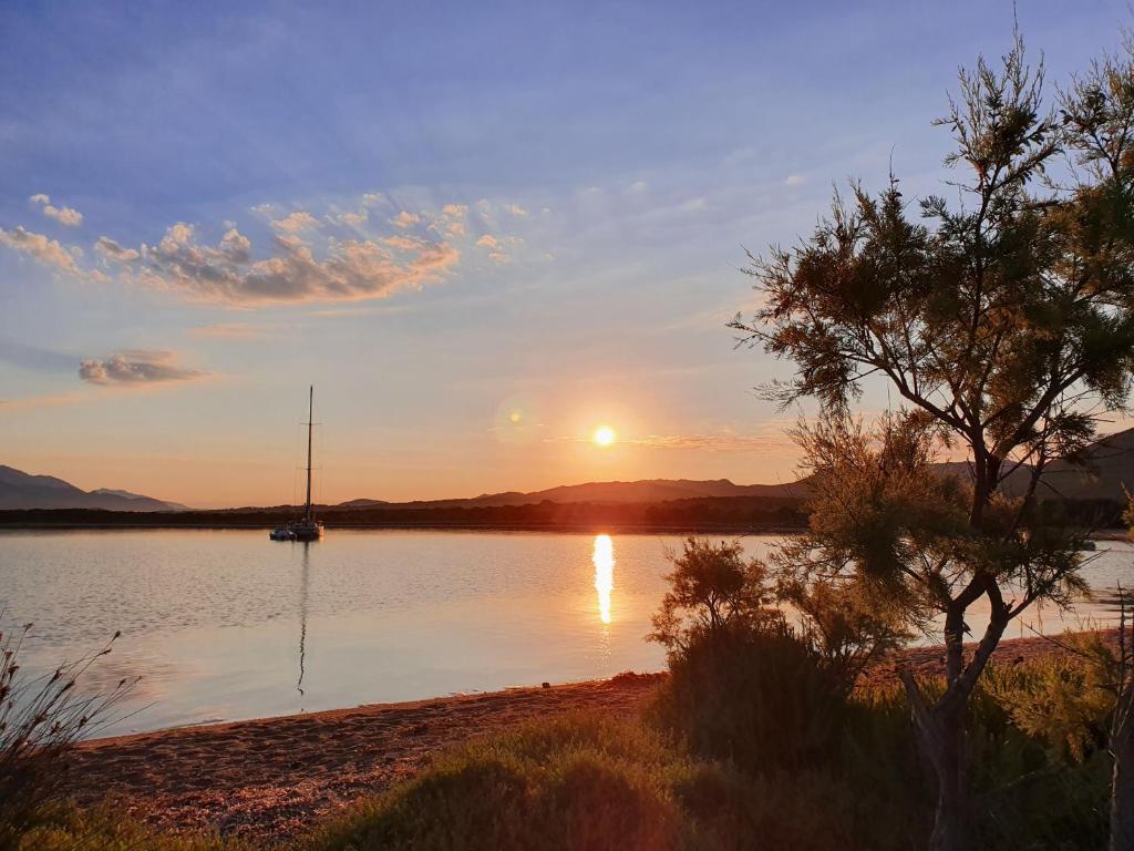 un coucher de soleil sur un lac avec un voilier dans l'eau dans l'établissement L'ortu di Quaprice, à Figari