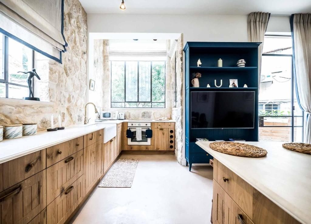 a kitchen with wooden cabinets and a large window at VELLER Mapu in Tel Aviv