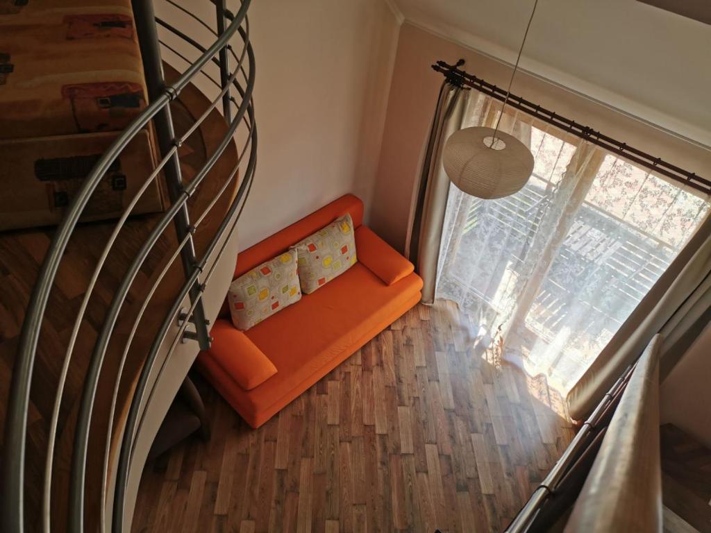 an orange couch in a room with a window at Tiborc Apartman in Gyula