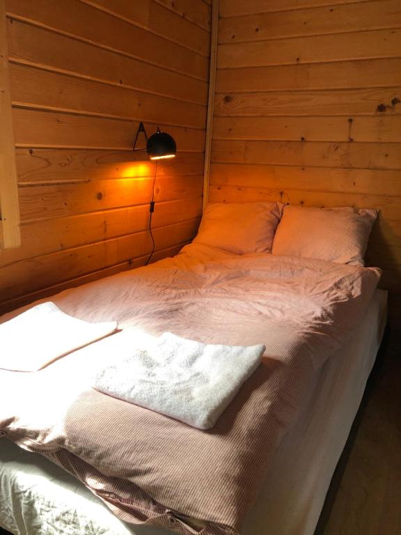 Una cama en una cabaña de madera con luz. en Domek drewniany, en Podzamcze