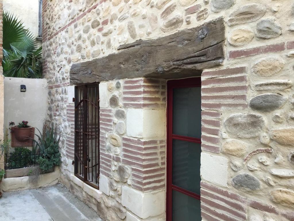 a stone building with a red door and a window at La maison d’Irma in Claira