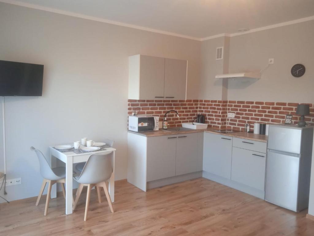 a kitchen with white cabinets and a table and chairs at Przytulny apartament w sercu Karkonoszy in Jelenia Góra