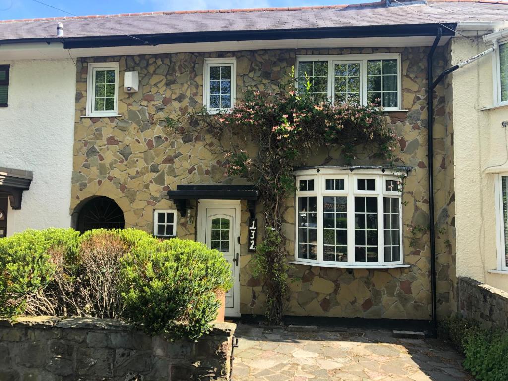 a stone house with flowers on the side of it at Cosy Rustic 3 bed cottage, great train links in Bebington