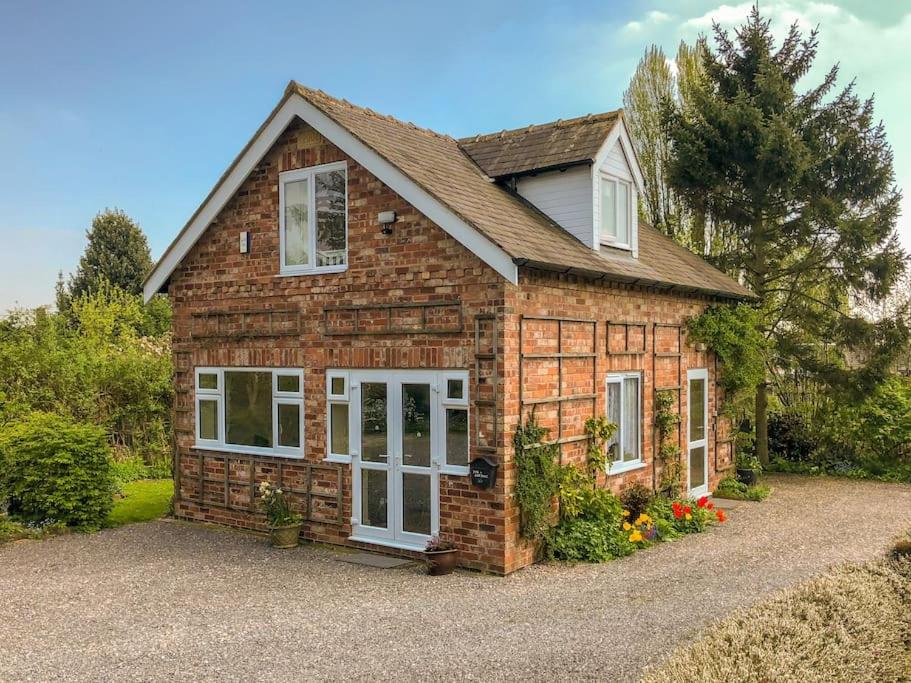 a brick house with white doors on a driveway at Highfield Cottage in West Hallam