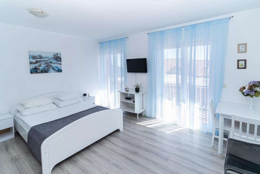 um quarto branco com uma cama e uma televisão em Benic Apartments em Mlini