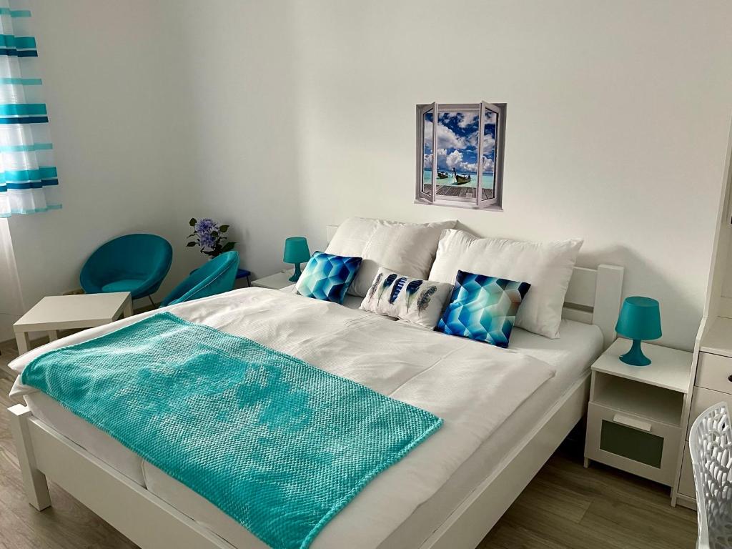 a bedroom with a white bed with blue pillows at Penzion u Vlčků in Cheb