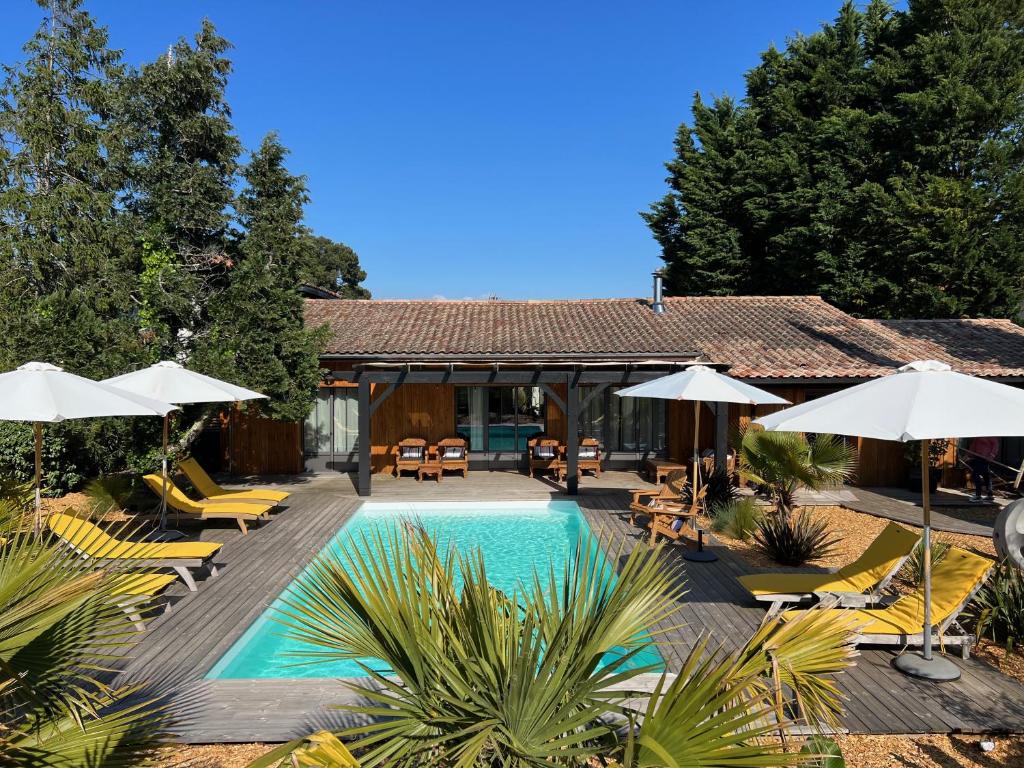 a swimming pool with lounge chairs and umbrellas at Villa-Arestel Chambres & Table d'hôtes in Arès