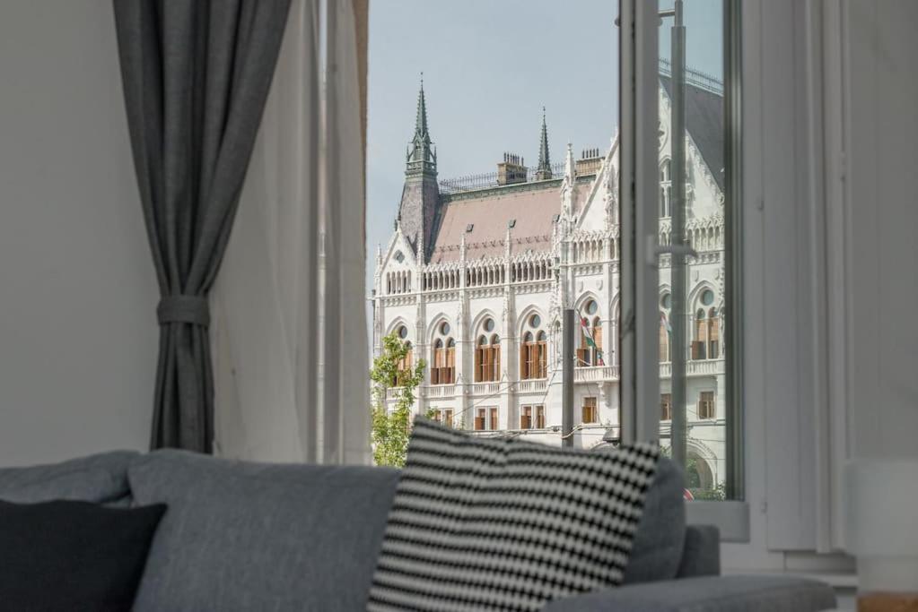 Hotel Parlament Panorama Luxury Apartman, a room with a couch and a window with a building at Parlament Panorama Luxury Apartman in Budapest