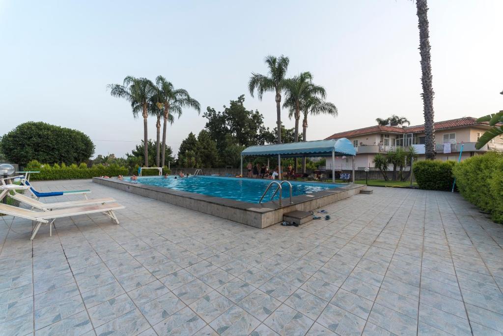 une grande piscine dans une cour avec des palmiers dans l'établissement Etna Perla Verde, à Fondachello