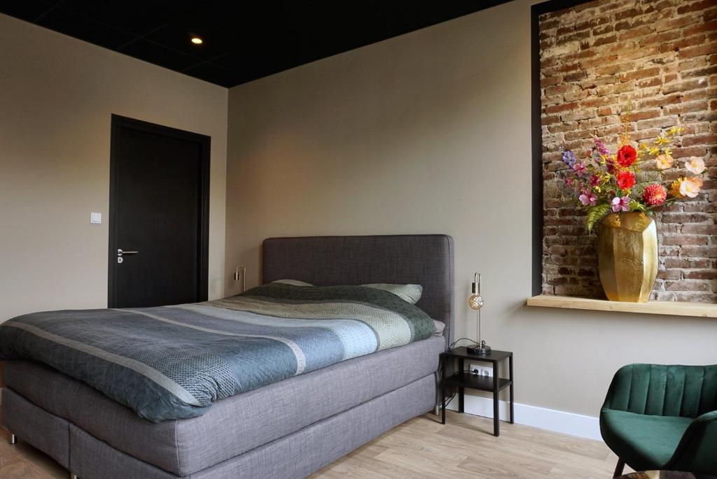 1 dormitorio con 1 cama y un jarrón de flores en la pared en B&Bie ons, en Bad-Nieuweschans
