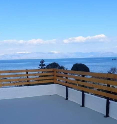 a wooden bench sitting on top of a building overlooking the ocean at Messonghi- La Pazzeli in Káto Spílaion