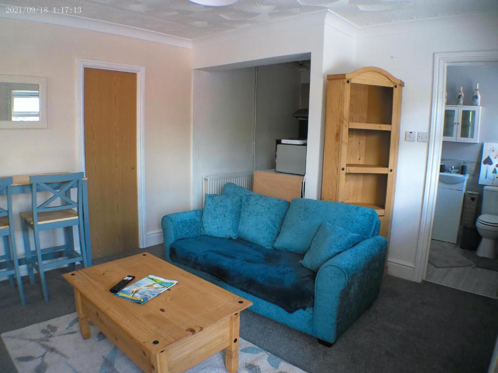 Sala de estar con sofá azul y mesa de centro en 1 bedroom Annex in the heart of Amman Valley en Bettws