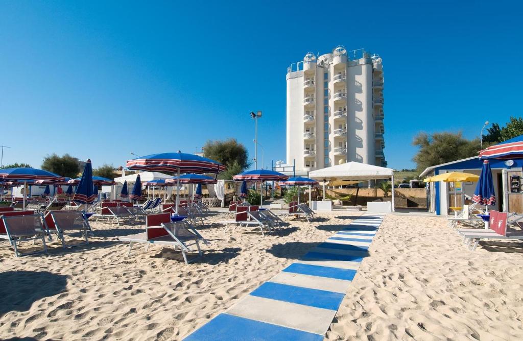 uma praia com cadeiras e guarda-sóis e um edifício em Hotel Nuovo Diana em Senigallia