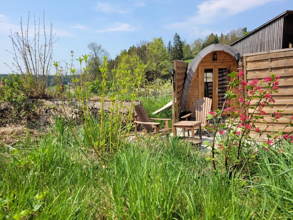 a wooden cabin with two chairs in the grass at Romantischer POD - Optional mit Hotpot - Whirlpool in Hohenberg an der Eger