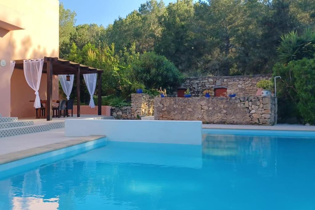 a swimming pool with blue water in front of a house at Can reganes in Sant Josep de Sa Talaia