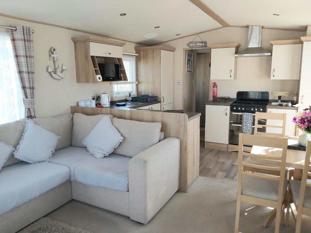 a living room with a couch and a kitchen at Vista Al Mar, Seaview Caravan Park, Whitstable in Kent