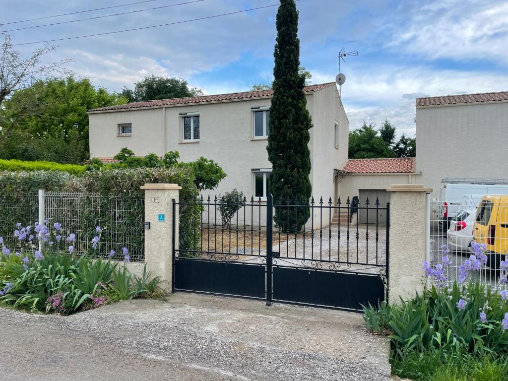 une porte en face d'une maison avec des fleurs violettes dans l'établissement La sommieroise, à Sommières