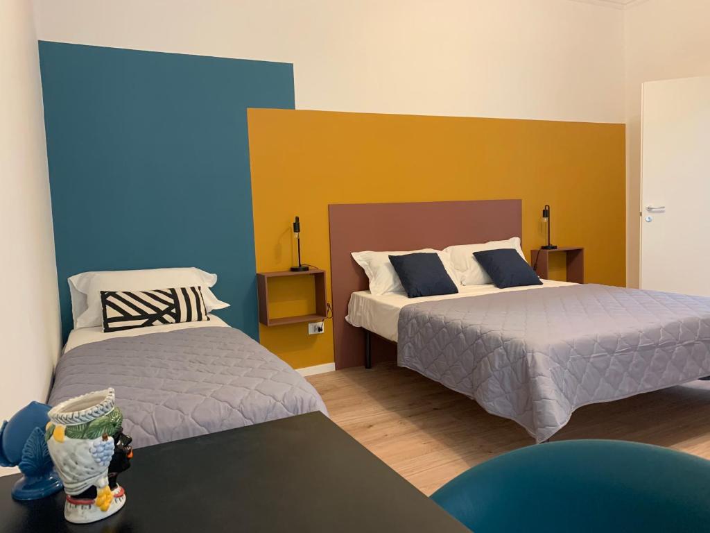 2 letti in una camera con blu e giallo di Dimora Lupo_LifeStyle B&B a Catania