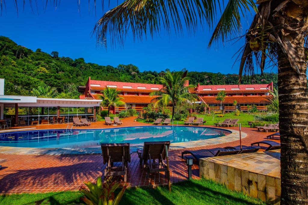 un complejo con piscina con sillas y un edificio en Hotel Boutique Frangipani, en Brotas