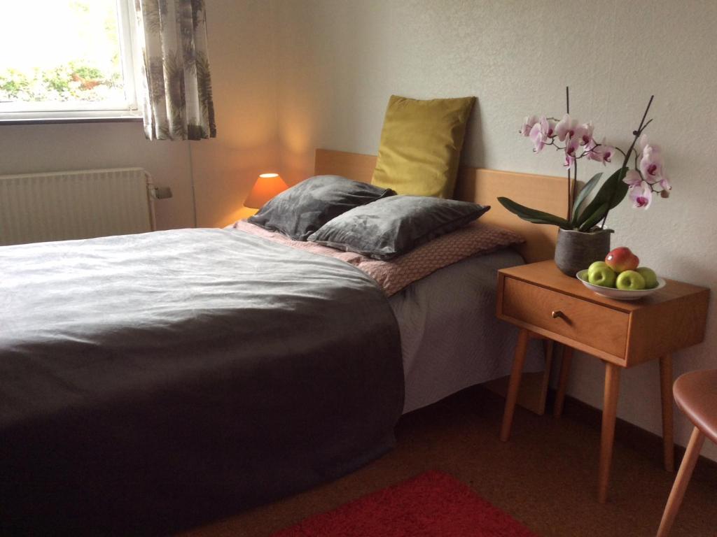 um quarto com uma cama e um vaso de flores sobre uma mesa em Single Room em Rødby