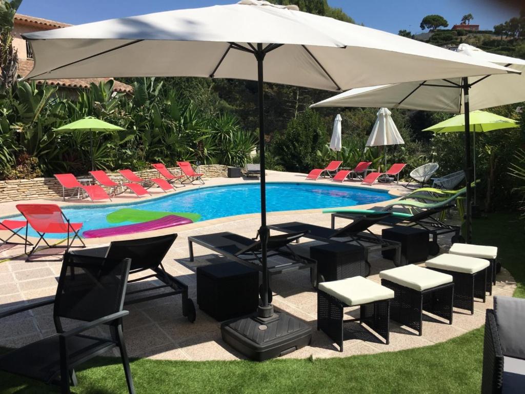 un grupo de sillas y una sombrilla junto a una piscina en VILLA LES YUCCAS - Pool - Sea view, en Cagnes-sur-Mer