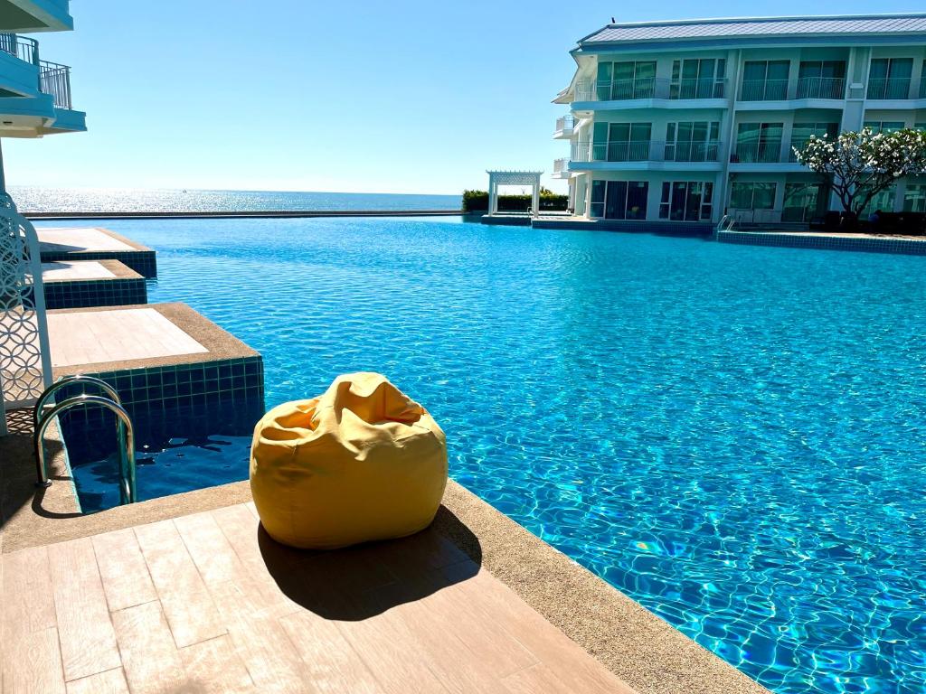 a large swimming pool with a yellow object in front of a building at On-the-Beach Seaview With Direct Pool Access - 1 Bedroom by Sweethome in Ban Bo Khaem
