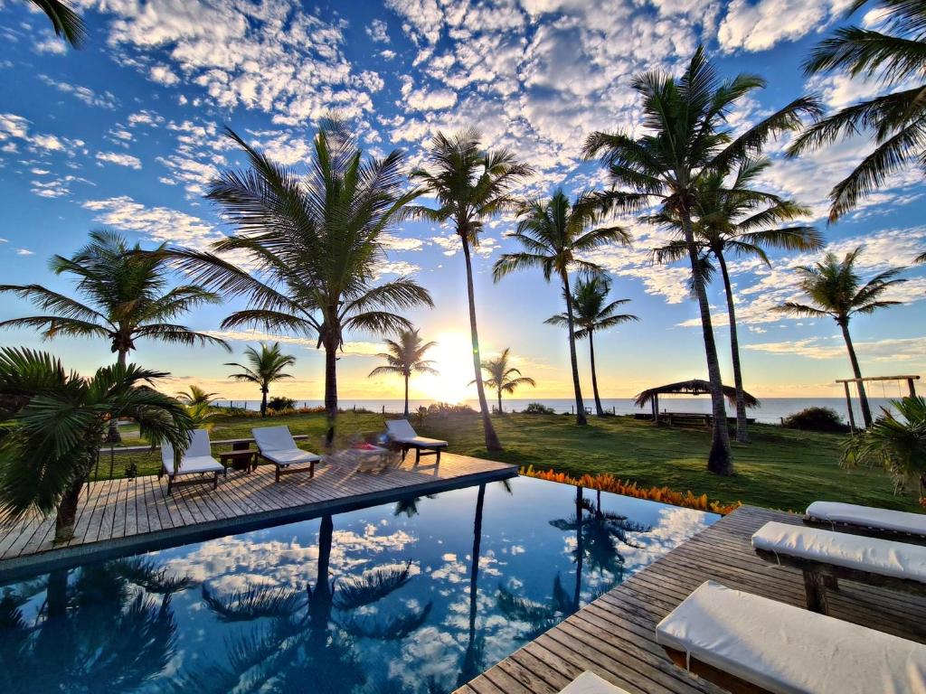 a swimming pool with palm trees and a sunset at Vila Bela Vista in Corumbau