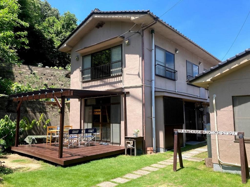 une maison avec une terrasse en bois dans la cour dans l'établissement ゲストハウス尾道ポポー Guesthouse Onomichi Pawpaw, à Onomichi