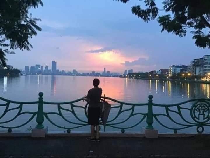 a person standing on a fence looking at the water at Best Price Hồ Tây Apartments for Long Stays in Hanoi