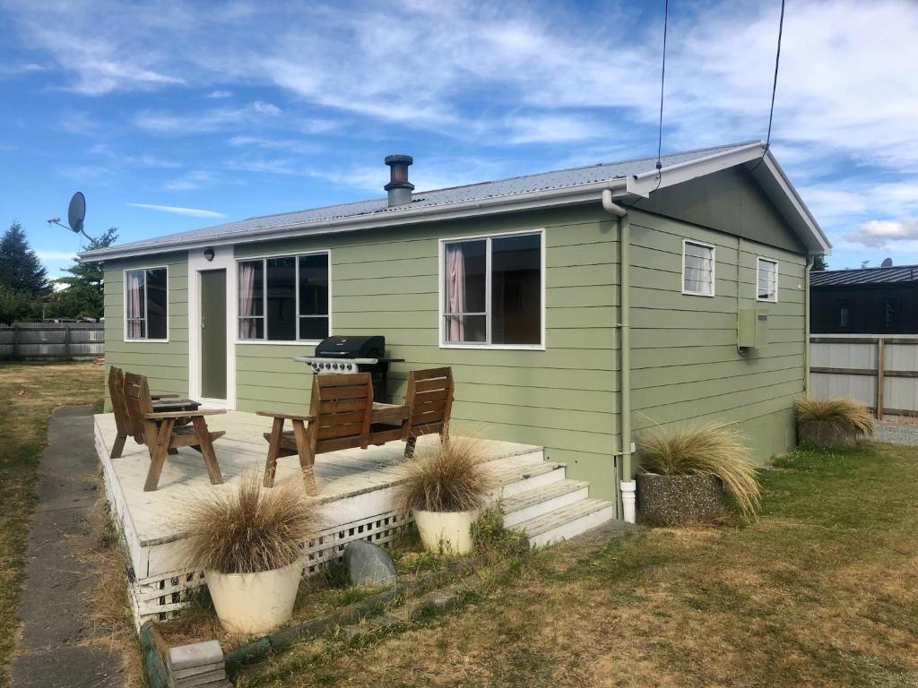 a green tiny house with a grill on a deck at Mackenzie Cottage in Twizel