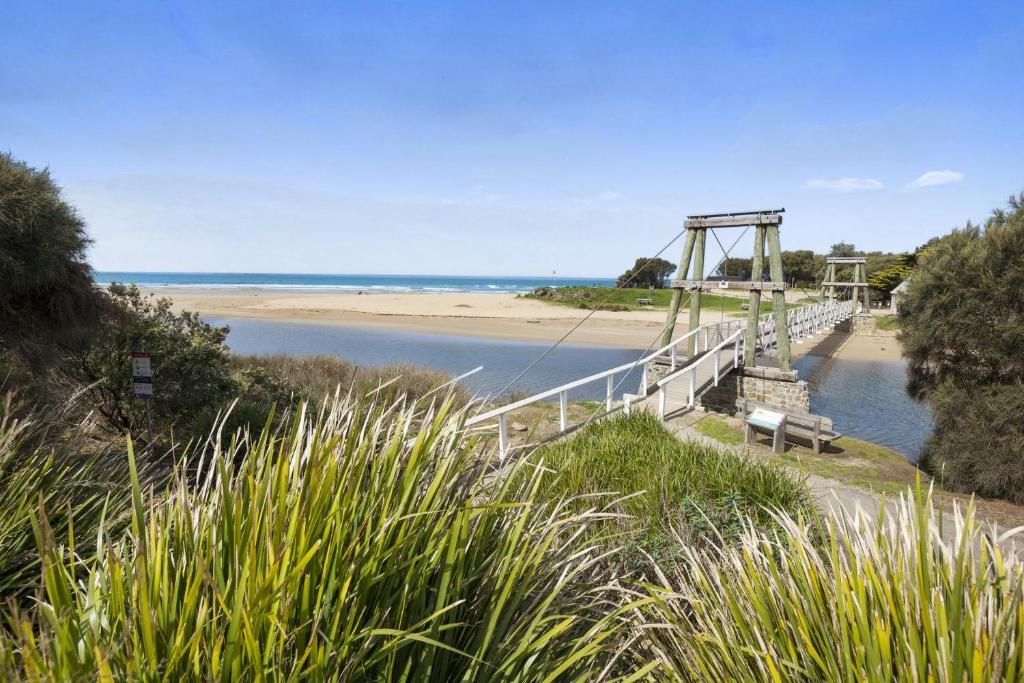 a bridge over a river next to a beach at Swingbridge in Lorne