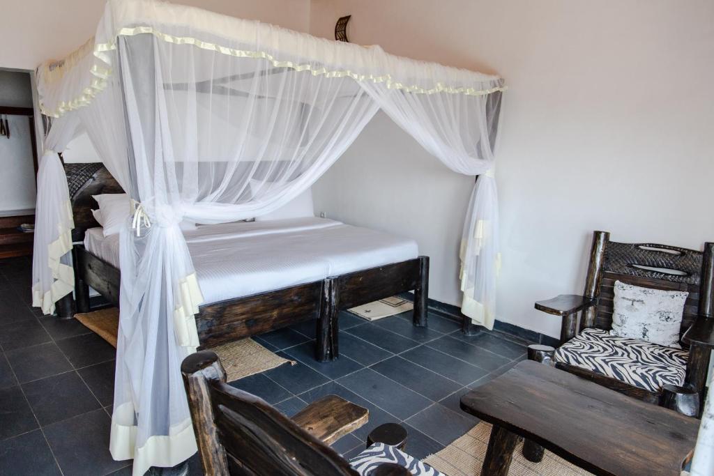 a bedroom with a canopy bed and a chair at Room in BB - Rushel Kivu Resort Ltd 