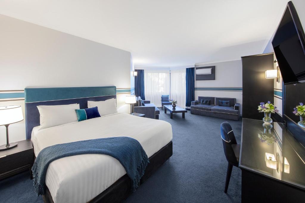 a hotel room with a bed and a living room at Ramada Diplomat Canberra in Canberra