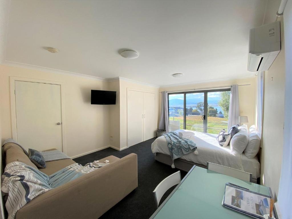 a living room with two beds and a couch at Poley Cow Studio Lakeviews in Jindabyne