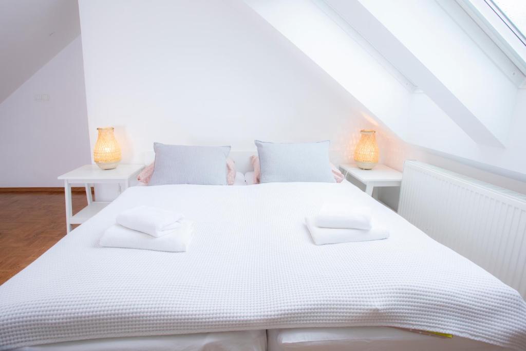 ein weißes Schlafzimmer mit einem weißen Bett und 2 Tischen in der Unterkunft Duplex Apartment Panj Kranjska Gora in Kranjska Gora