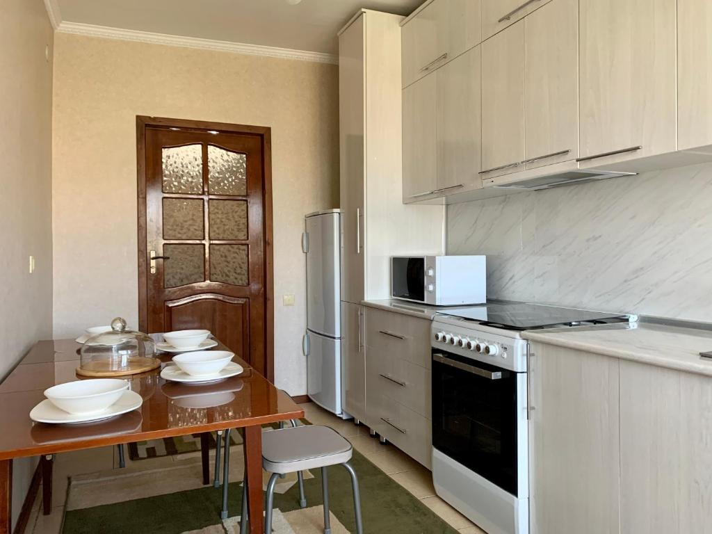 uma cozinha com uma mesa e um fogão forno superior em Apartment in the centre of Karakol em Karakol