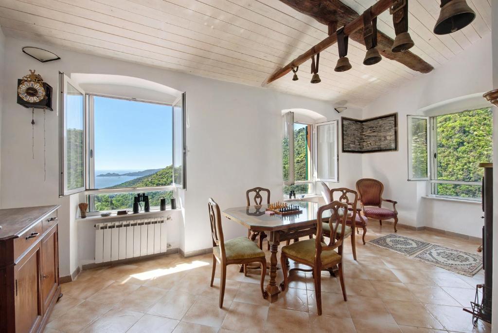 a dining room with a table and chairs and windows at Cottage con vista mare in Zoagli